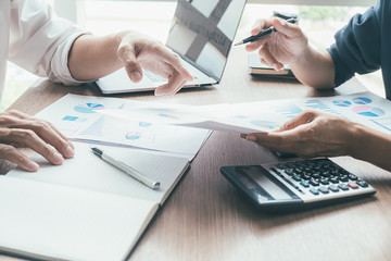 Concept of young business working at his coffee shop and using laptop, holding smartphone in hand discussing the charts and graphs showing the results of their successful teamwork.