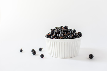 Ripe black currant or blueberries in a small white Cup on a white background. Black currant harvest. Healthy food. vegetarian food