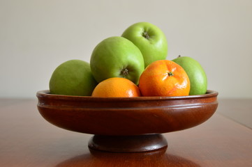 A Wooden bowl filled with apples and oranges
