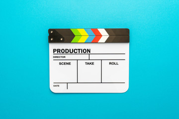 Top view of professional white acrylic clapperboard. Flat lay image of empty movie clapboard over turquoise blue background. Central composotion of cinematography production concept.