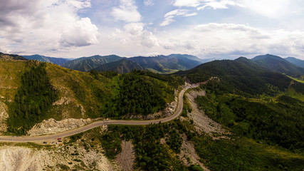 Naklejka premium A landscape view of beautiful fresh green forest, road Chui tract and Altai mountain background. Panoramic view of beautiful green forest in the Altai mountains