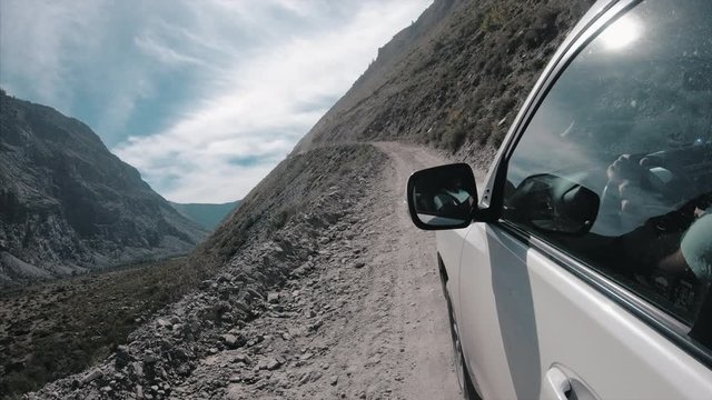 Car moves along the graver bumpy road in mountains and climbs the hill