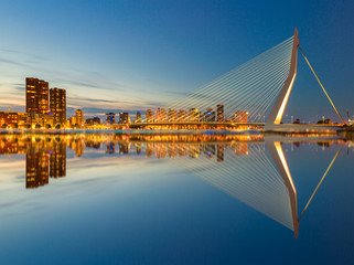 The Erasmusbrug and the Rotterdam skyline by night with a reflection in the water, a famous landmark in the Netherlands and travel destination