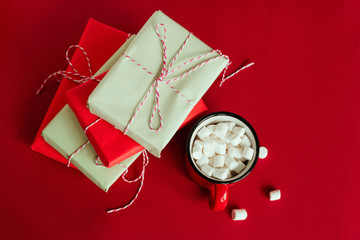top view gift boxes and cup with marshmallows on red background