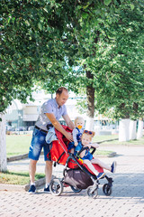 father walks with children, stroller, summer, caucasian family