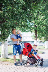 Obraz premium father walks with children, stroller, summer, caucasian family