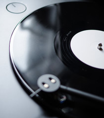 new black vinyl record with blank white label spinning on turntable with defocused modern round...