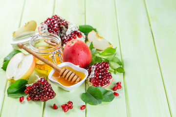 Rosh hashana jewish holiday concept - apples, honey, pomegranate, green wood background