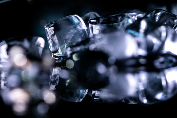 pile of different ice cubes on reflection table on black background 
