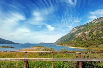 Fototapeta na wymiar Panoramic view of Tierra del Fuego National Park, showing small islands surrounded by green vegetation and water, against a blue sky.
