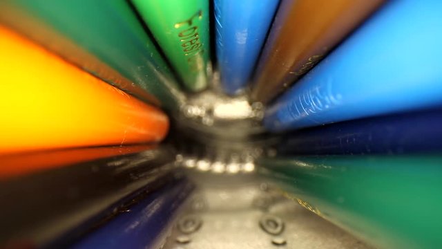 Moving out of a jar of colored pencils. Pencils roll and fall over the top of the lens ending up to reveal the tips. Using a wide angle probe lens to get a unique perspective.