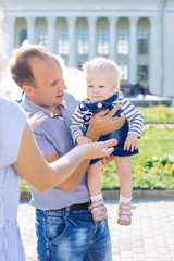 summer, caucasian family, father keep baby girl in arms, parents play daughter, city park