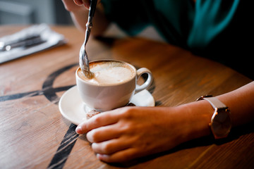the girl is waiting for a meeting and drinks cappuccino