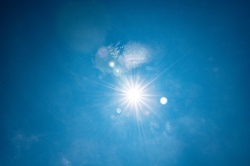 sun star creates flare on a blue summer sky