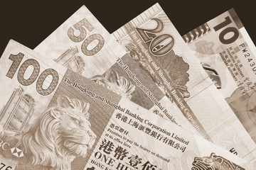 Different Hong Kong dollars bills on a dark background close up. Money background brown color toned