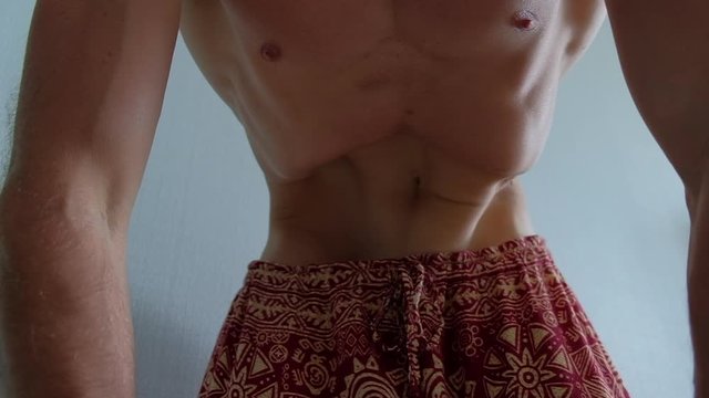 Young man with muscular body does Nauli cleaning exersice. At some point man seamlessly reverses the way of motion
