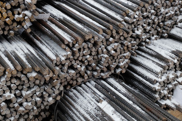 Steel snow covered reinforcement bars at the outdoor warehouse, industrial background, building armature