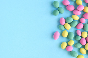 Colored sweets, peanut covered with glaze on blue background composition.