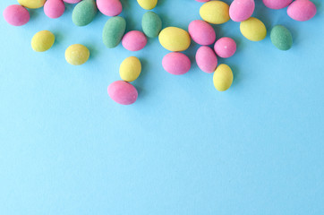 Colored sweets, peanut covered with glaze on blue background composition.