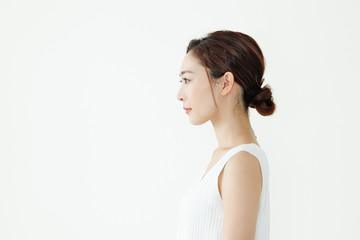 Fototapeta premium まとめ髪の女性の横顔。ノースリーブを着ている。