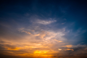 Naklejka na ściany i meble Twilight dramatic blue sky with white fluffy clouds and bright orange sunlight.