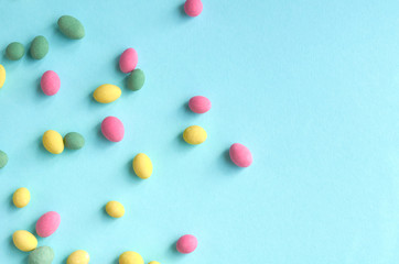 Colored sweets, peanut covered with glaze on blue background composition.
