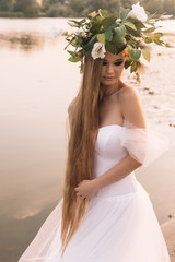 Fototapeta na wymiar beautiful girl in a white dress, a wreath and golden hair
