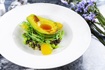 Close up view on tasty grilled avocado with creamy spicy butter on pad with quinoa, greens and microgreen. Restaurant food style. Healthy, balanced, vegan food for lunch. Salad bowl.