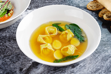 Close up view chicken broth with pasta and potatoes in white bowl. Healthy, balanced food for lunch. Dinner soup. Picture for recipe, menu or poster. Marble table. Flat lay