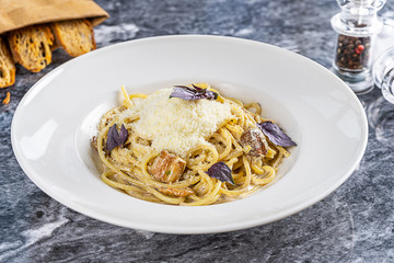 Close up view on italian tasty pasta with wild mushrooms and parmesan, cream sauce and basil served on marble table. Spaghetti. Mediterranean and italian cuisine. Restaurant food for lunch