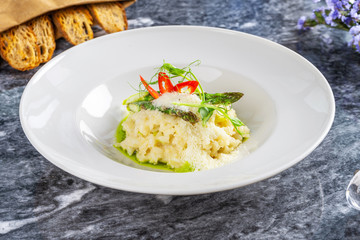 Close up view on tradtional and tasty risotto with parmesan, asparagus and chili. Mediterranean and italian cuisine. Restaurant food for lunch. Flat lay food on marble table. Picture for recipe. vegan