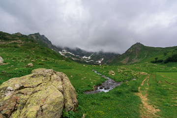 tourist trail to the lake .  snowy mountains around. panorama of mountainous terrain