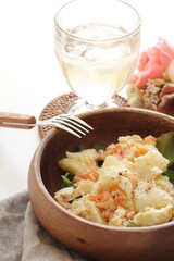 Potato and carrot salad on wooden bowl