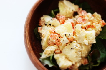 Potato and carrot salad on wooden bowl
