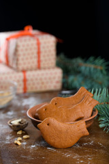 Christmas gingerbread cookies in the form of a bird on the table. Gifts, sprigs of spruce, walnuts.