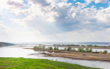 Sunny spring day on meadow near river. Scenic rural landscape. Spring sunny background.