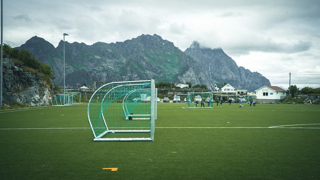  Empty training gate for classic fotbal on green grass playground on Lofoten Islands surrounded by rocks and stones. Sport in Norway, Henningsvaer, Nordland