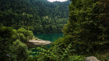 Natural landscape. Panorama view of the lake Small Ritsa. Trees reflecting in the blue from lapis lazuli water. Ritsa National Park, Abkhazia