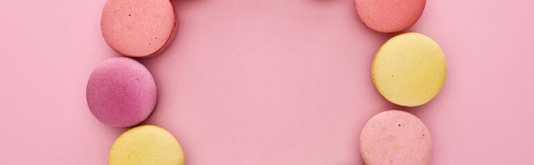 frame of multicolored delicious French macaroons on pink background, panoramic shot