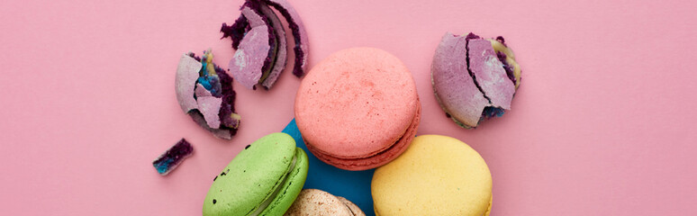 top view of multicolored delicious French macaroons in blue postal envelope on pink background, panoramic shot