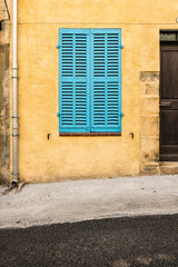 Fototapeta na wymiar Closed blue shutters on a vintage yellow wall in a street in France
