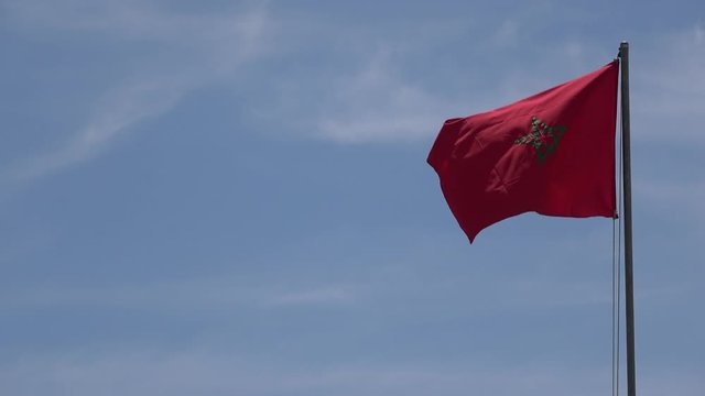 4K. Ultra HD. Beautiful big flag of Morocco waving in the wind. Blue sky with clouds. The red flag has a star in the center that represents the Seal of Solomon of Morocco. Muhammad.