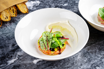 Close up view on salmon tartare served with bread, sauce and parsley on white plate. Tartare fish flat lay. Seafood with copy space for design on marble table