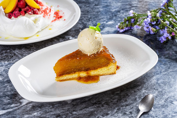 Apple Pie with ice cream and caramel. Piece of tasty hot apple tart and ice cream on white plate. Dessert food on marble table. Restaurant food photo for menu, poster or banner. Copy space