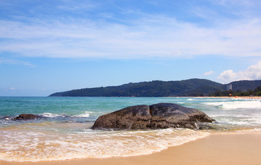 Boulders, the surf, and the blue sky over the sea, Karon sandy beach, Thailand