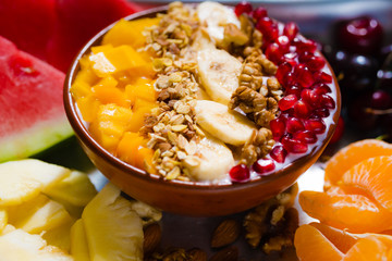 Smoothie bowl with colorful tropical fruits on serving tray, top view from above.