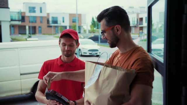 Man pays delivery man for home grocery delivery with credit card