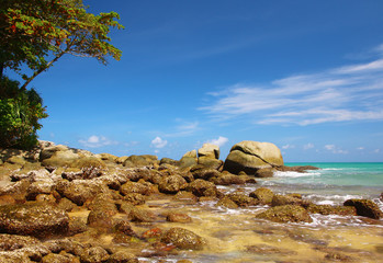 Boulders, the surf, and the blue sky over the sea, Karon sandy beach, Thailand