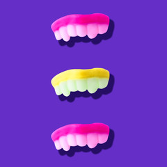 Photography collage of trendy neon pink and yellow colors human teeth on purple background top view flat lay isometric pattern.Halloween symbol.Poster in pop-art and style
