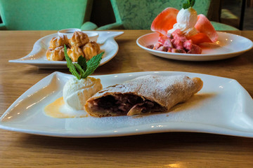strudel cake - dough stuffed with cherries and jam, served with a scoop of vanilla ice cream and mint leaves. Profitero cake - air pastry with custard filling. Coffee with marshmallows. European recip